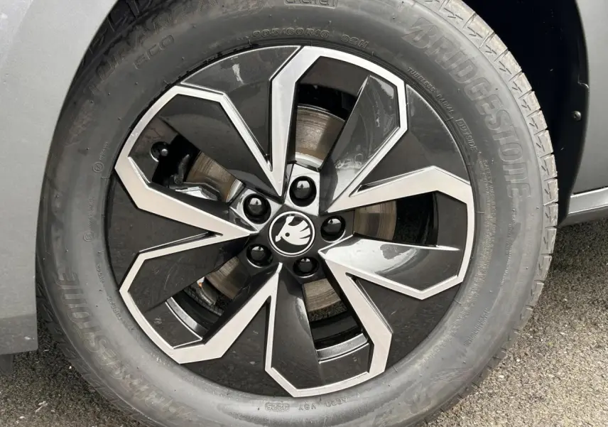 Gros plan sur la jante alliage 16 pouces au design noir et argent du SKODA KAMIQ gris graphite, côté roue avant.