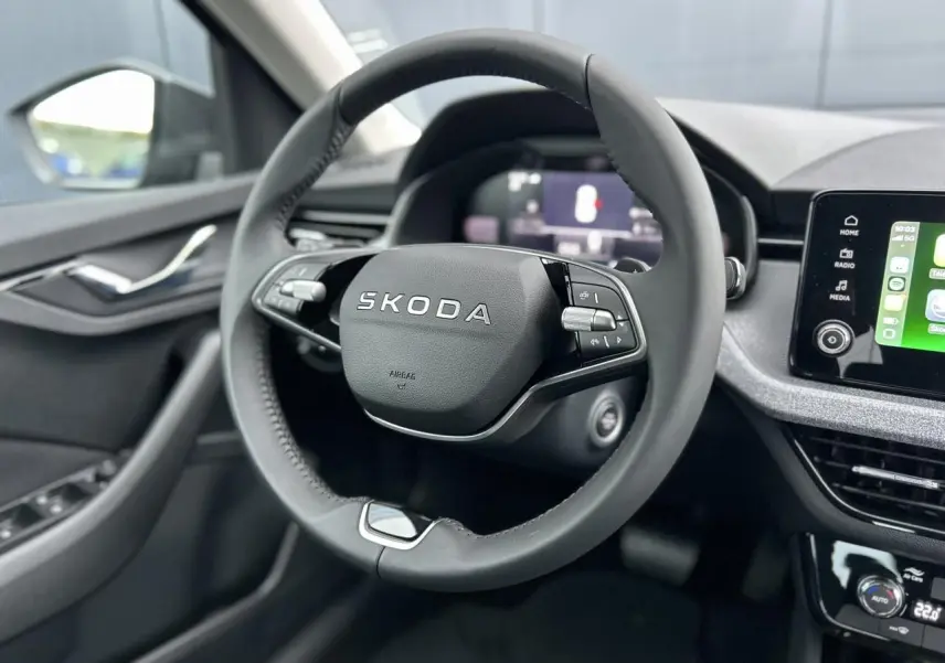 Vue rapprochée du volant cuir noir multifonctions d’une Skoda Kamiq 2025 avec écran tactile et commandes intégrées.