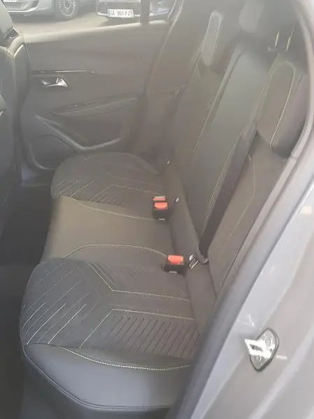 Vue intérieure côté gauche des sièges arrière en tissu et cuir gris d'une Peugeot 208 Hybrid 110 e-DCS6 GT 2025, avec ceinture rouge visible.
