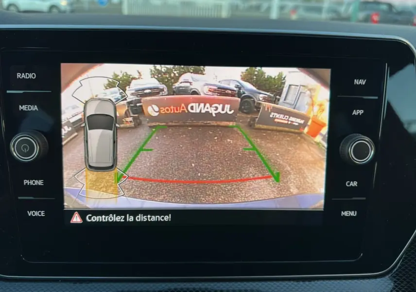 Écran de caméra de recul du Volkswagen T-Cross gris cendré, affichant les lignes de guidage et l'alerte de distance.