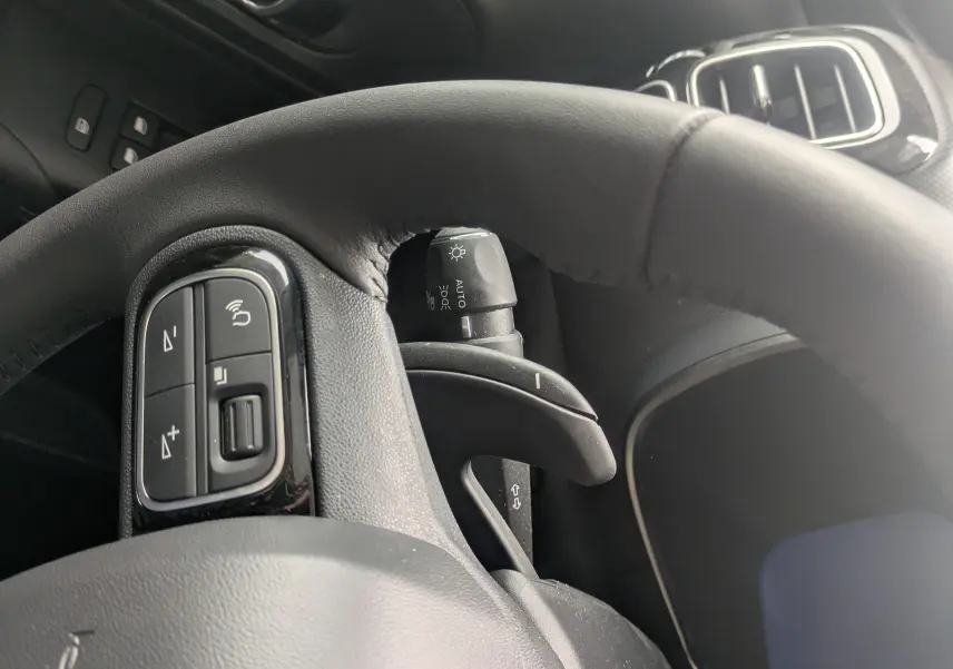 Vue rapprochée du volant en cuir et du tableau de bord noir du Citroën C5 Aircross hybride blanc, avec commandes au volant visibles.