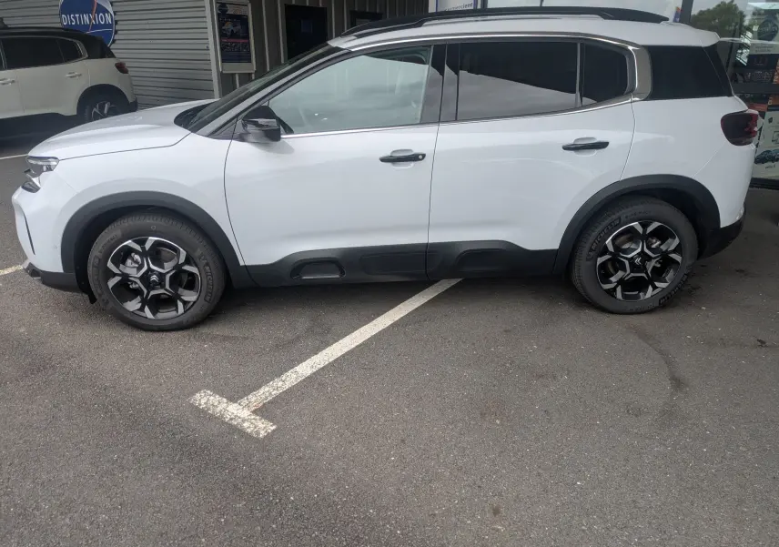 Profil droit d'un Citroën C5 Aircross hybride blanc Okenite avec jantes alliage 18 pouces biton et vitres arrière surteintées.