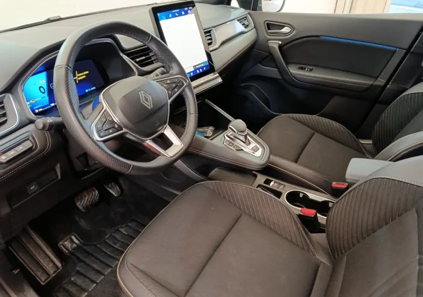 Vue intérieure côté conducteur de la Renault SYMBIOZ noire, avec volant multifonctions et grand écran tactile vertical.