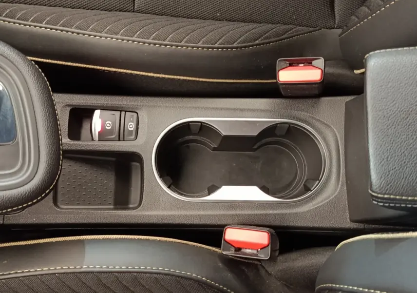 Vue plongeante sur la console centrale noire du Renault Symbioz avec porte-gobelets et bouton frein à main électrique.