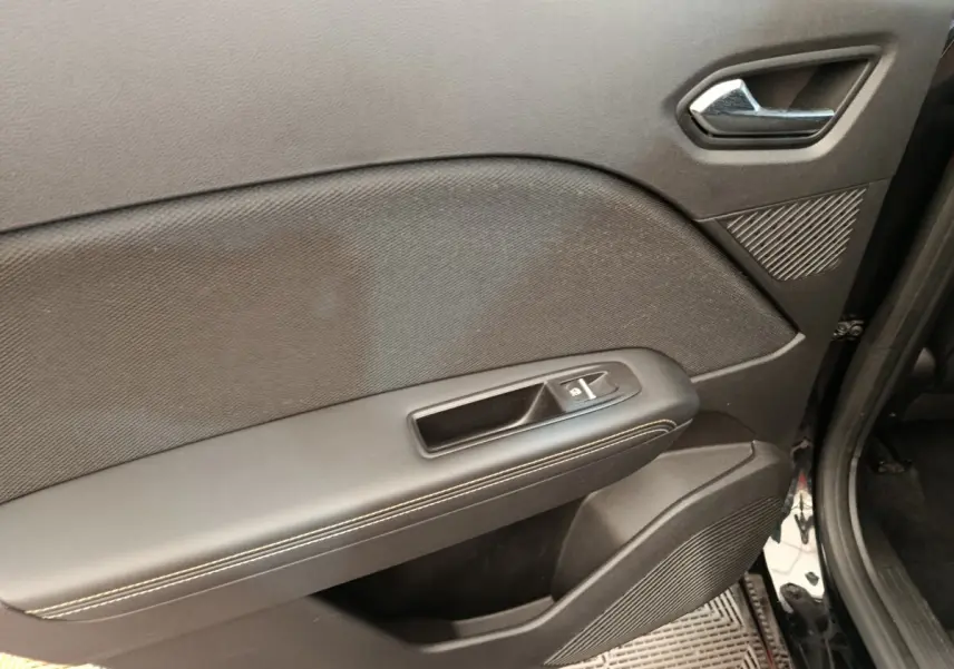 Vue rapprochée de la porte avant droite noire du Renault Symbioz, avec poignée intérieure et commande de fenêtre.