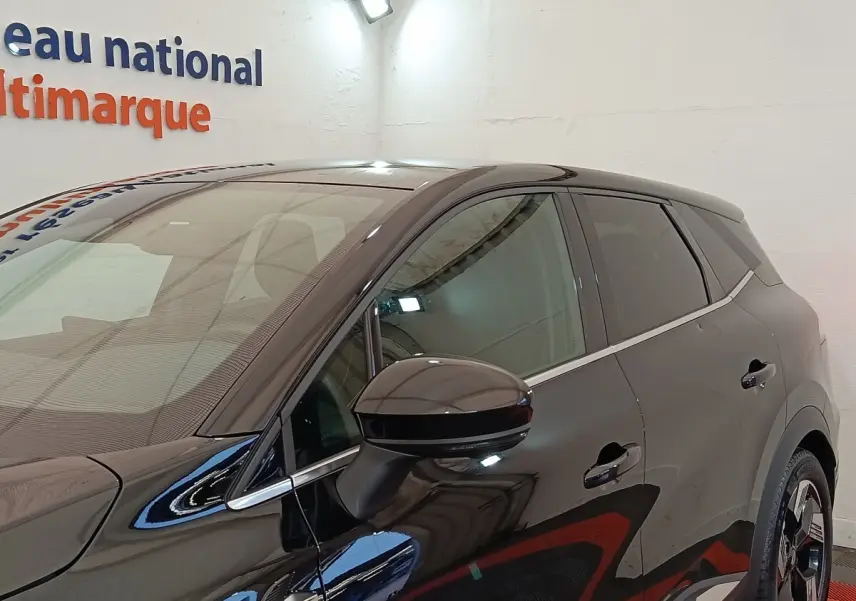 Vue latérale droite d'une Renault SYMBIOZ noire avec rétroviseur et jantes distinctives visibles en intérieur showroom.