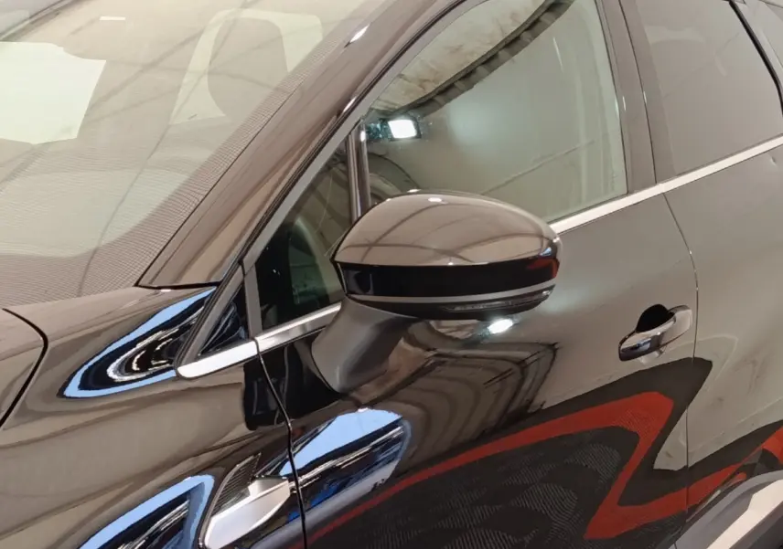 Détail du rétroviseur côté gauche d’une Renault Symbioz noire avec poignée de porte et vitre avant visibles.