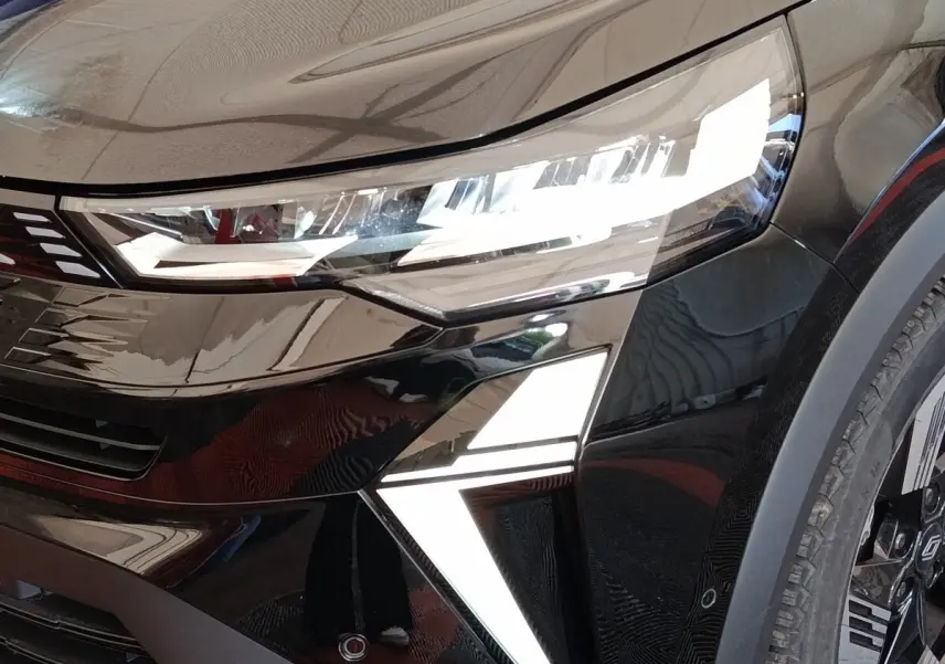 Gros plan sur l'avant droit noir brillant du Renault SYMBIOZ 2025 avec phares LED et feux diurnes en forme de flèche.
