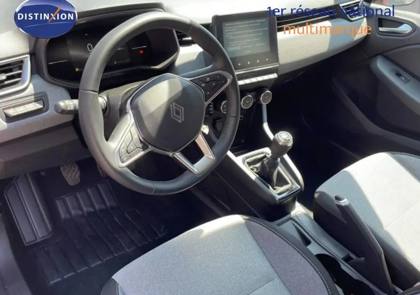 Vue intérieure de face du poste de conduite d'une Renault Clio 2025, volant cuir multifonction et levier de vitesse manuel visibles.