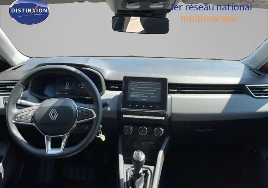 Vue intérieure avant du tableau de bord de la Renault Clio rouge flamme, avec volant cuir et écran tactile central.