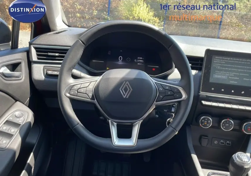 Vue intérieure centrée sur le volant cuir multifonction d'une Renault Clio 2025 avec tableau de bord numérique et écran tactile.