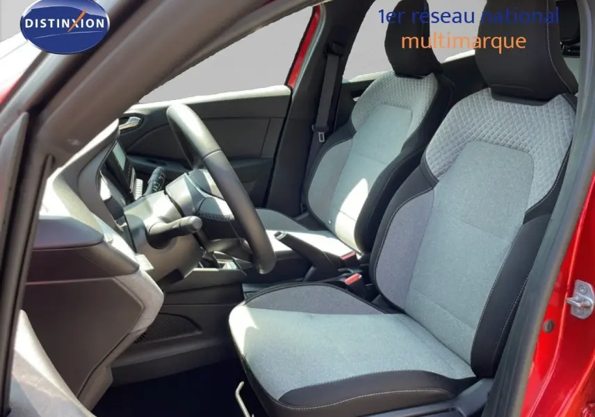 Vue intérieure côté gauche de la Renault Clio 2025 rouge flamme métal, montrant les sièges tissu gris et volant cuir multifonction.
