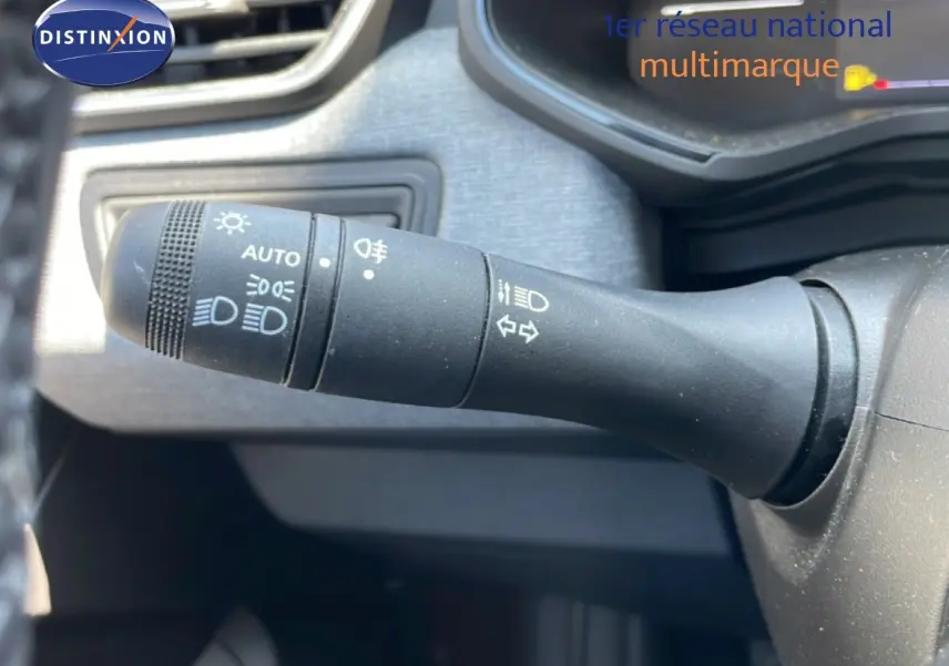 Gros plan sur la commande des phares et clignotants dans l’habitacle d’une Renault Clio rouge flamme 2025.
