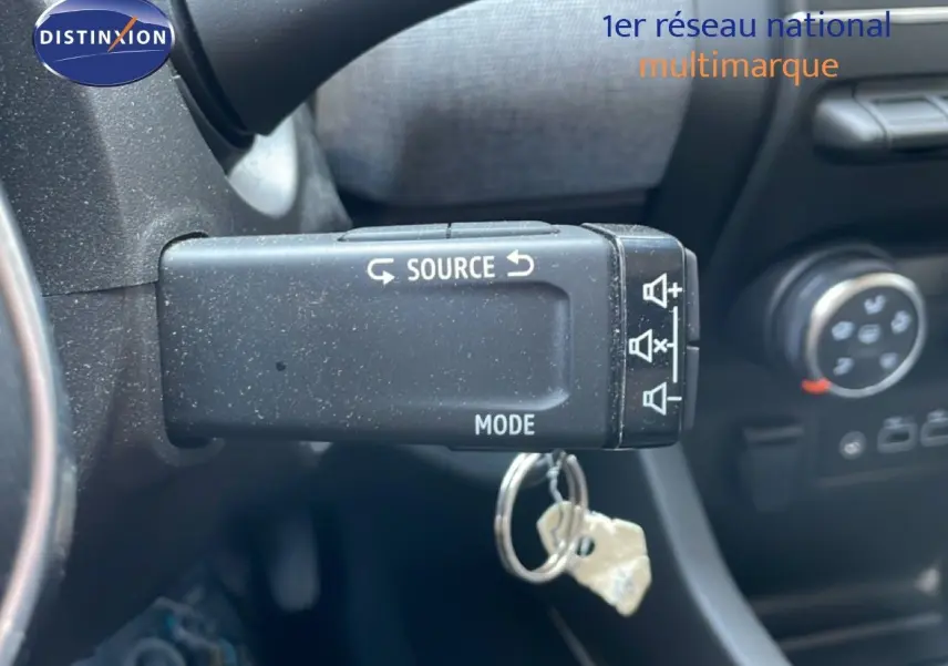 Gros plan sur la commande au volant de la Renault Clio 2025, avec touches source et mode visibles dans l’habitacle noir.