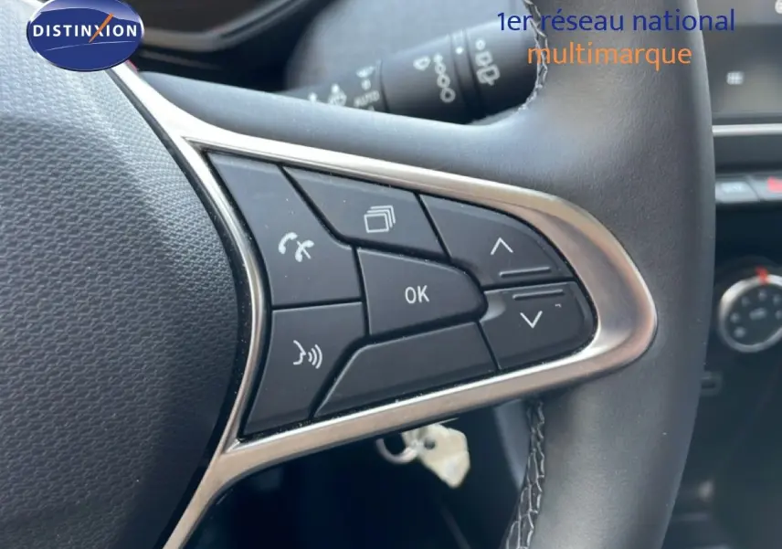 Gros plan sur les commandes au volant en cuir noir de la Renault Clio 2025, avec boutons multifonctions et finition argentée.