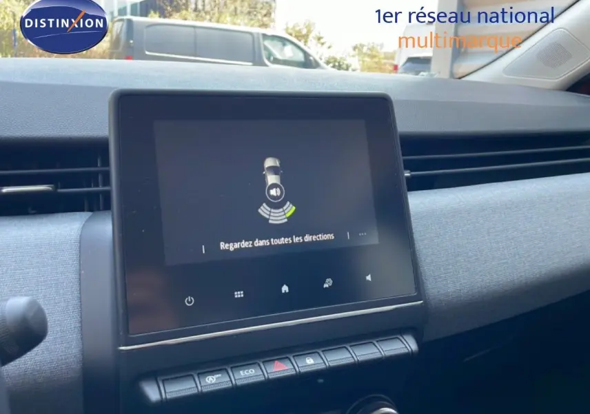 Vue intérieure du tableau de bord de la Renault Clio rouge flamme, avec écran tactile central et commandes climatisation visibles.