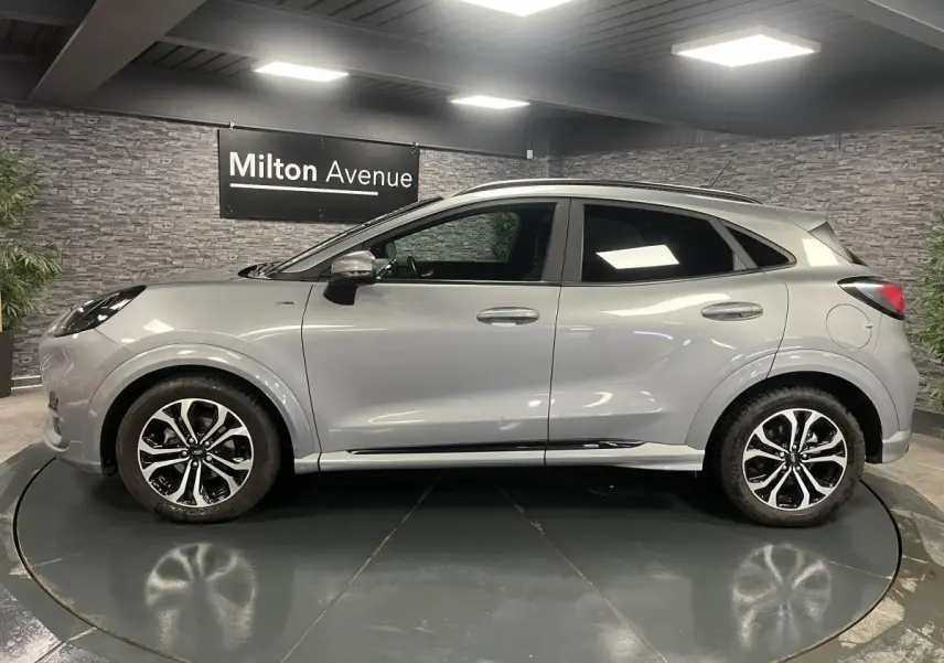 Ford Puma gris Solar en vue profil côté gauche, avec barres de toit noires et jantes alliage 17 pouces.