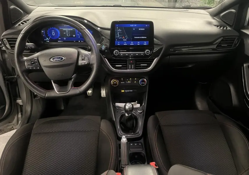 Vue intérieure avant du Ford Puma gris, tableau de bord noir avec écran tactile central et volant sport ST-Line.