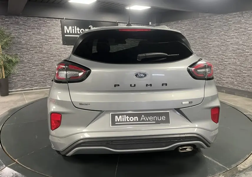 Vue arrière d'un Ford Puma gris métallisé avec feux LED et sortie d'échappement chromée dans un showroom.