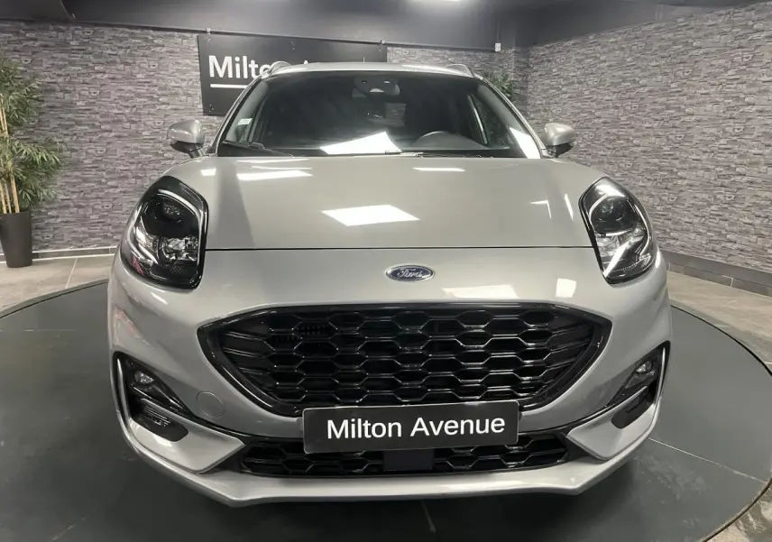 Vue avant d'un Ford Puma gris métallisé avec calandre noire et phares Full LED dans un showroom.