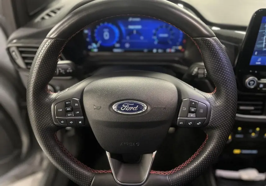 Volant cuir noir à surpiqûres rouges du Ford Puma ST Line 2021 avec commandes intégrées et tableau de bord numérique bleu.