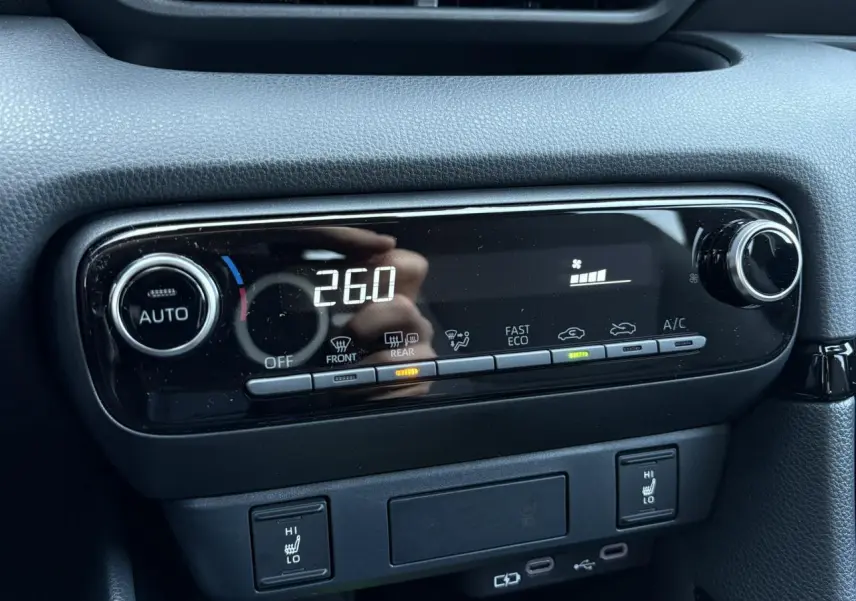 Gros plan sur la console centrale de la Toyota Yaris Hybride 2025, affichant la climatisation automatique et les sièges chauffants.