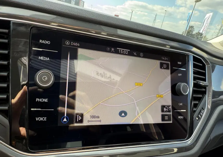 Écran tactile central du Volkswagen T-Roc blanc 2022 affichant la navigation, vue intérieure côté conducteur.