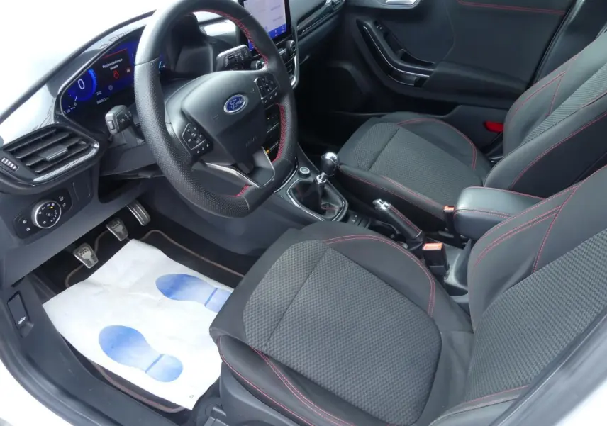 Intérieur avant du Ford Puma blanc 2020, sièges tissu noir avec surpiqûres rouges et volant ST-Line à méplat.