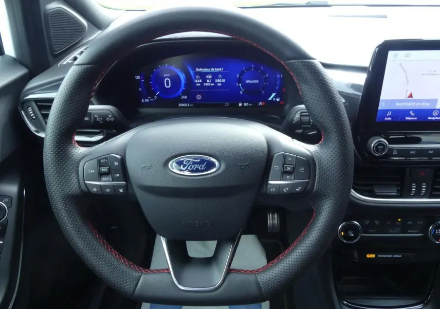 Vue intérieure centrée sur le volant perforé noir avec surpiqûres rouges du Ford Puma 2020, tableau de bord numérique et écran tactile.
