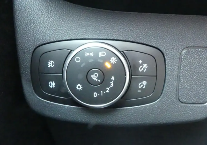 Gros plan sur la commande d'éclairage intérieure du Ford Puma 1.0 EcoBoost blanc, avec bouton rotatif allumé.