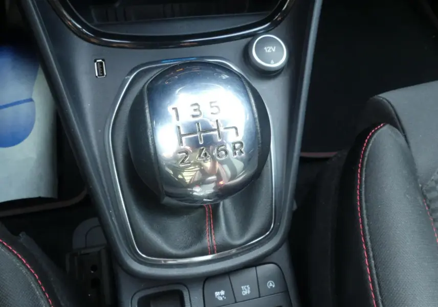 Gros plan sur le levier de vitesses manuel chromé avec surpiqûres rouges du Ford Puma blanc finition ST Line.