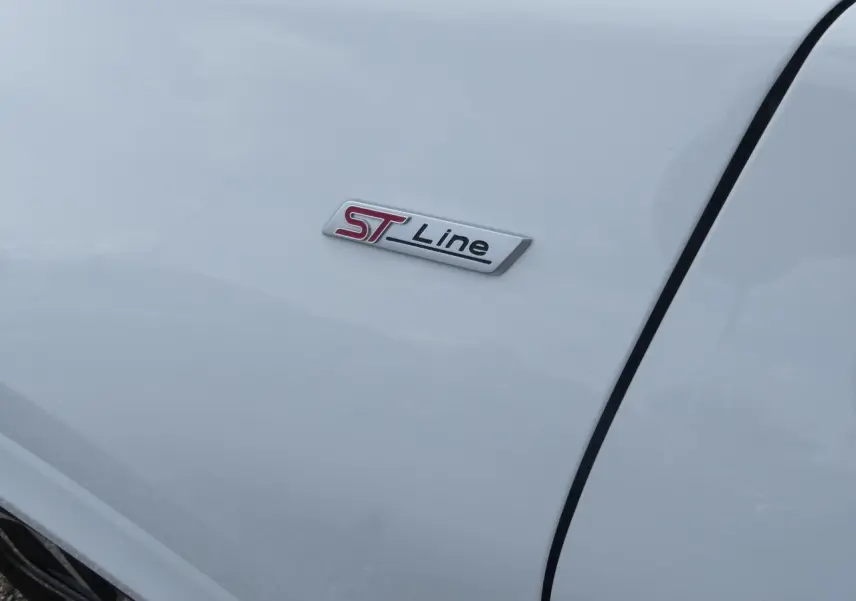 Gros plan sur l'écusson ST Line rouge et noir sur la porte blanche d'une Ford Puma 2020.