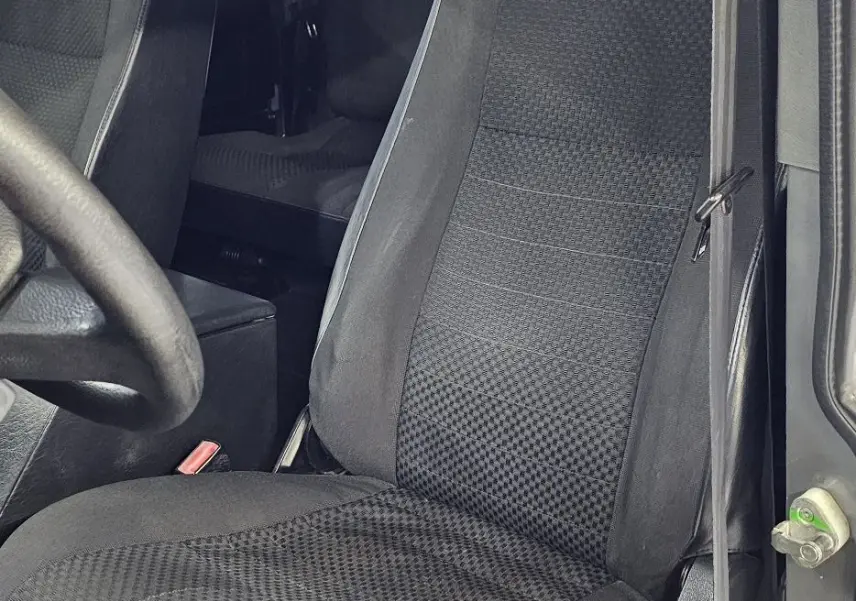 Gros plan sur le siège avant droit noir à motifs du Land Rover Defender 110 II Station Wagon gris de 2010.