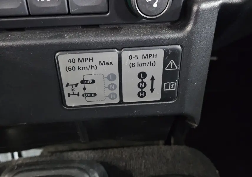 Gros plan sur l'autocollant des vitesses de transfert du Land Rover Defender 110 II gris, version Station Wagon S de 2010.