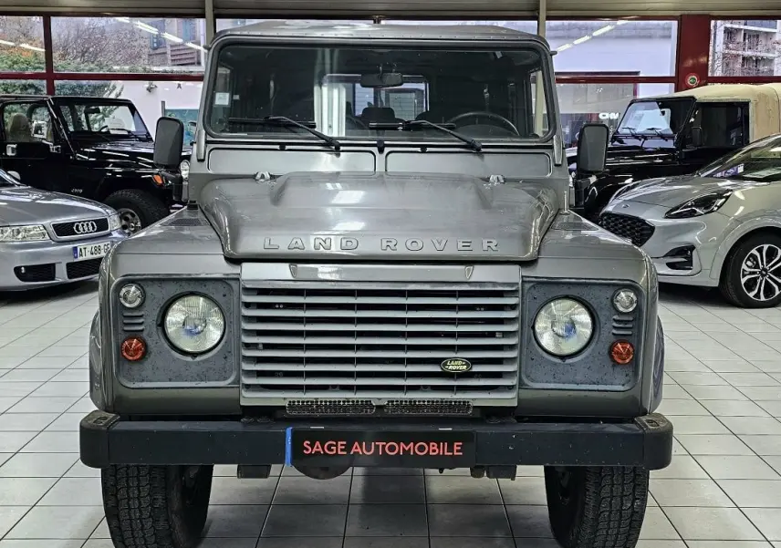 Vue frontale d'un Land Rover Defender 110 Station Wagon S gris 2010, avec calandre distinctive et phares ronds.
