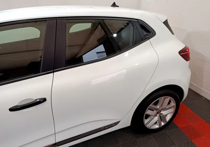 Vue côté gauche arrière d'une Renault Clio blanche avec poignées noires et jantes alliage argentées.