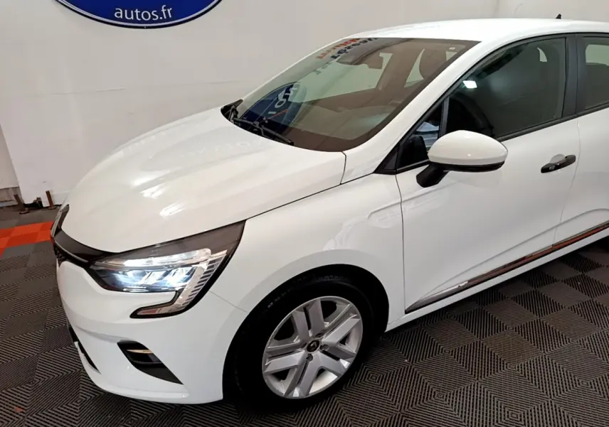 Renault Clio Business blanche vue de 3/4 avant droit, avec phares LED allumés et jantes alliage visibles.