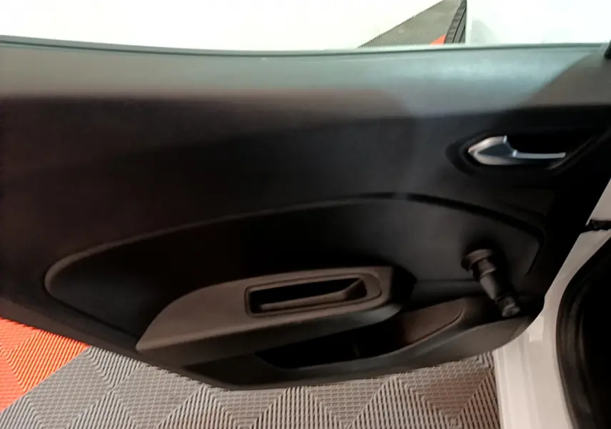 Vue rapprochée de la porte côté droit d’une Renault Clio Business blanche, avec poignée et manivelle de vitre manuelle.