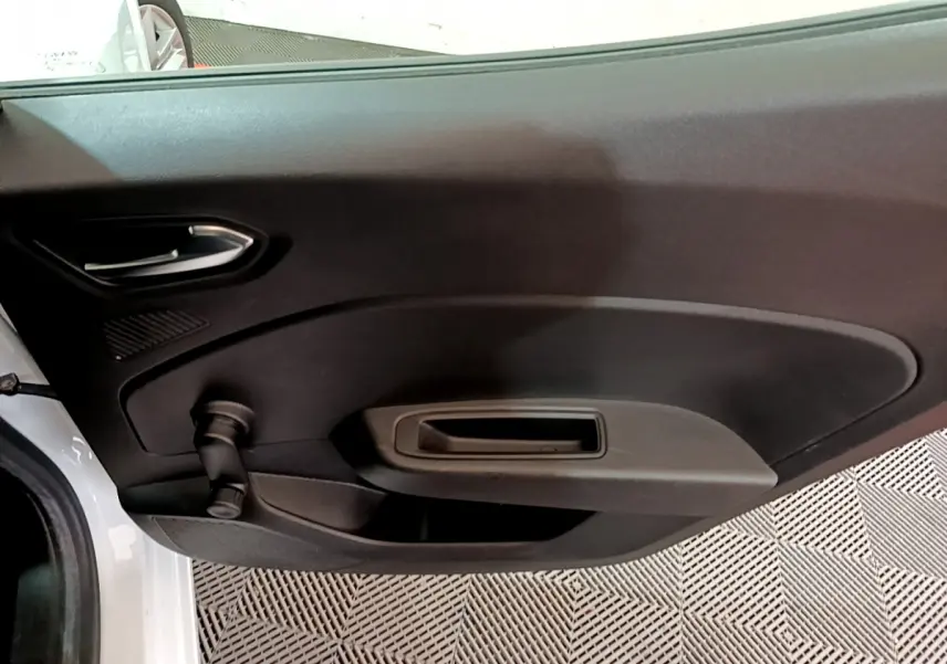 Vue rapprochée de la porte intérieure côté gauche d'une Renault Clio Business blanche, avec poignée et commande de vitre manuelle.