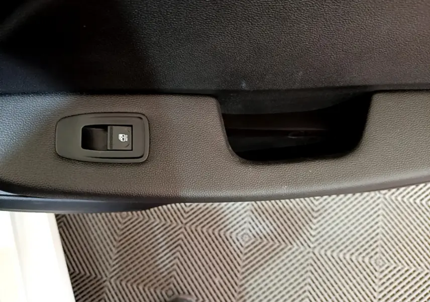 Détail de la commande de verrouillage centralisé sur la porte intérieure côté gauche d'une Renault Clio Business blanche.