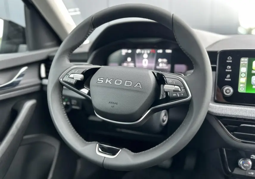 Gros plan sur le volant cuir multifonctions de la Skoda Kamiq 2025, avec tableau de bord digital et écran tactile visible.