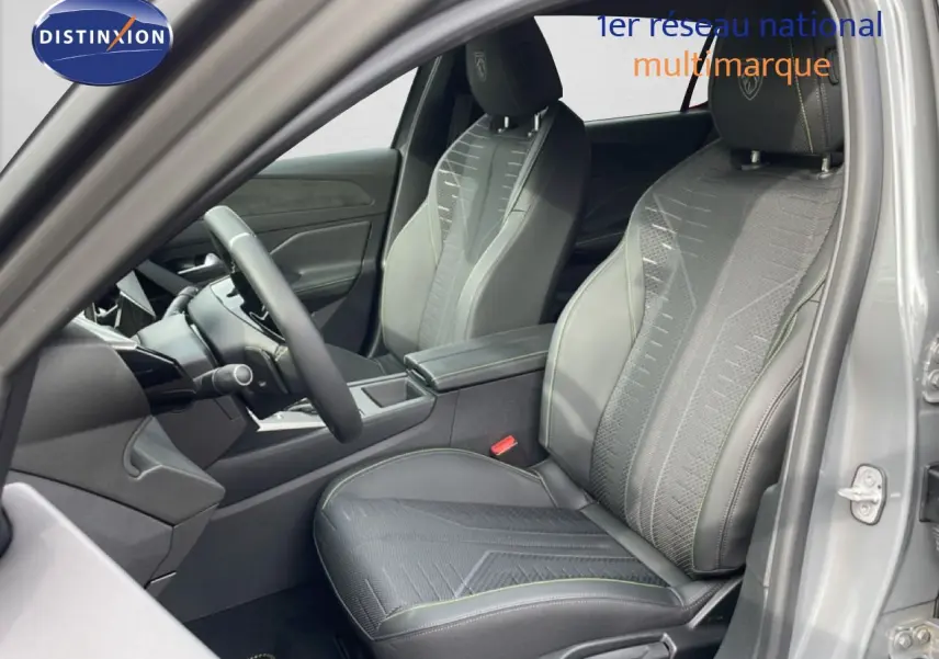 Vue intérieure côté conducteur de la Peugeot 308 gris selenium metal, sièges en tissu et cuir avec surpiqûres vertes.