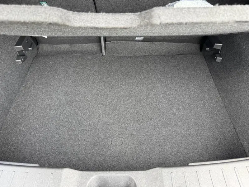 Vue intérieure du coffre spacieux et tapissé de tissu gris du Nissan Juke 2025 noir Kuro métallisé.