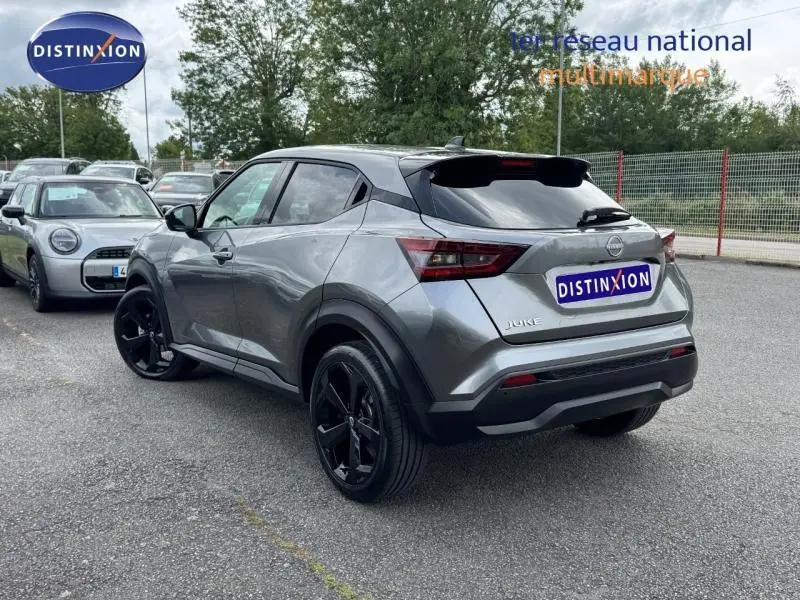 Vue 3/4 arrière droite d'un Nissan Juke 2025 gris métallisé avec jantes noires et lignes anguleuses marquées.