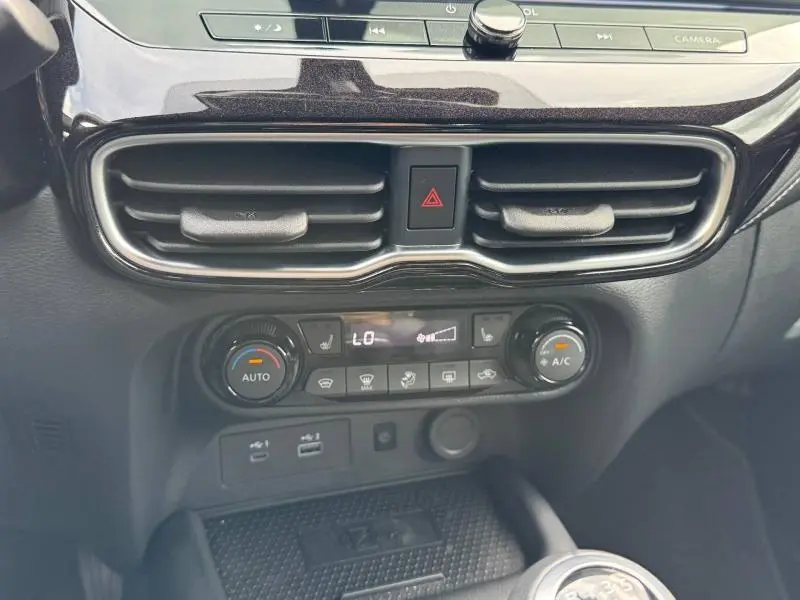 Vue rapprochée de la console centrale noire Kuro métallisée du Nissan Juke 2025 avec commandes climatisation et boutons multifonctions.