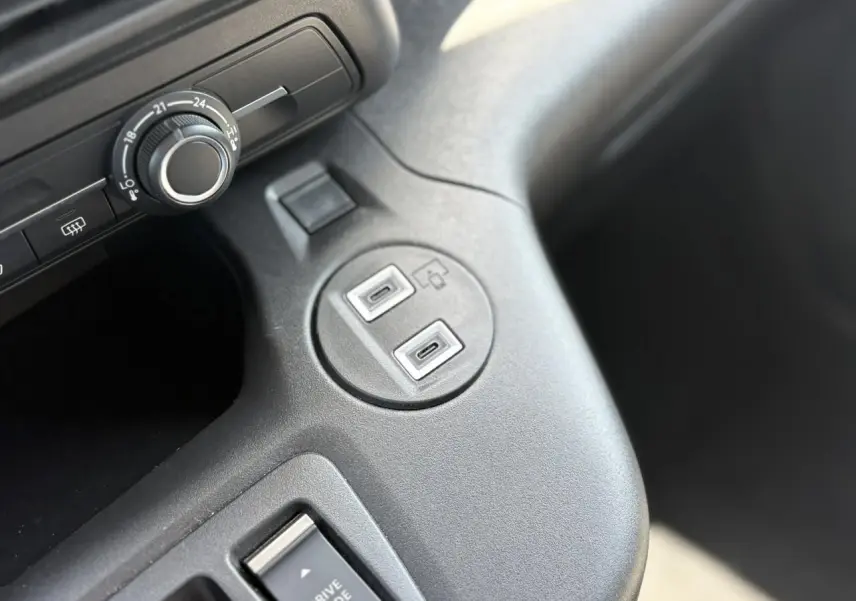Gros plan sur la console centrale du Citroën Berlingo ë-136 avec deux ports USB-C et un bouton de réglage de température.
