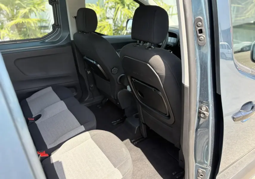 Vue intérieure côté droit du Citroën Berlingo bleu Kiama 2025, montrant la banquette arrière et les sièges avant avec tablettes rabattables.