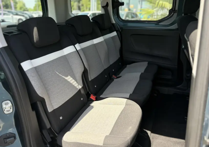 Vue intérieure sur la banquette arrière grise et noire du Citroën Berlingo ë-136 2025, avec porte coulissante ouverte.