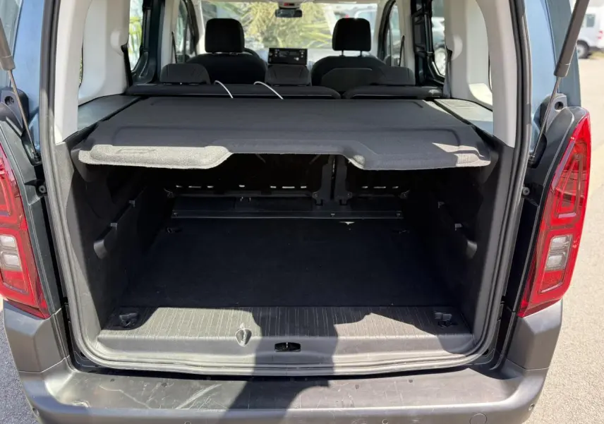 Coffre ouvert vu de l'arrière d'un Citroën Berlingo ë-136 bleu Kiama avec cache-bagages déployé.
