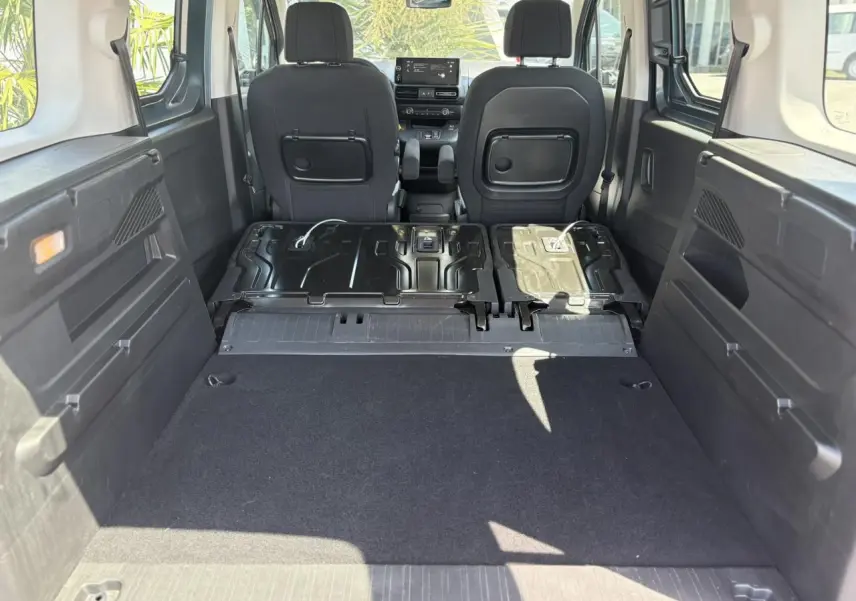 Vue intérieure arrière du Citroën Berlingo ë-136 2025, montrant la banquette rabattue et l'espace de chargement noir.